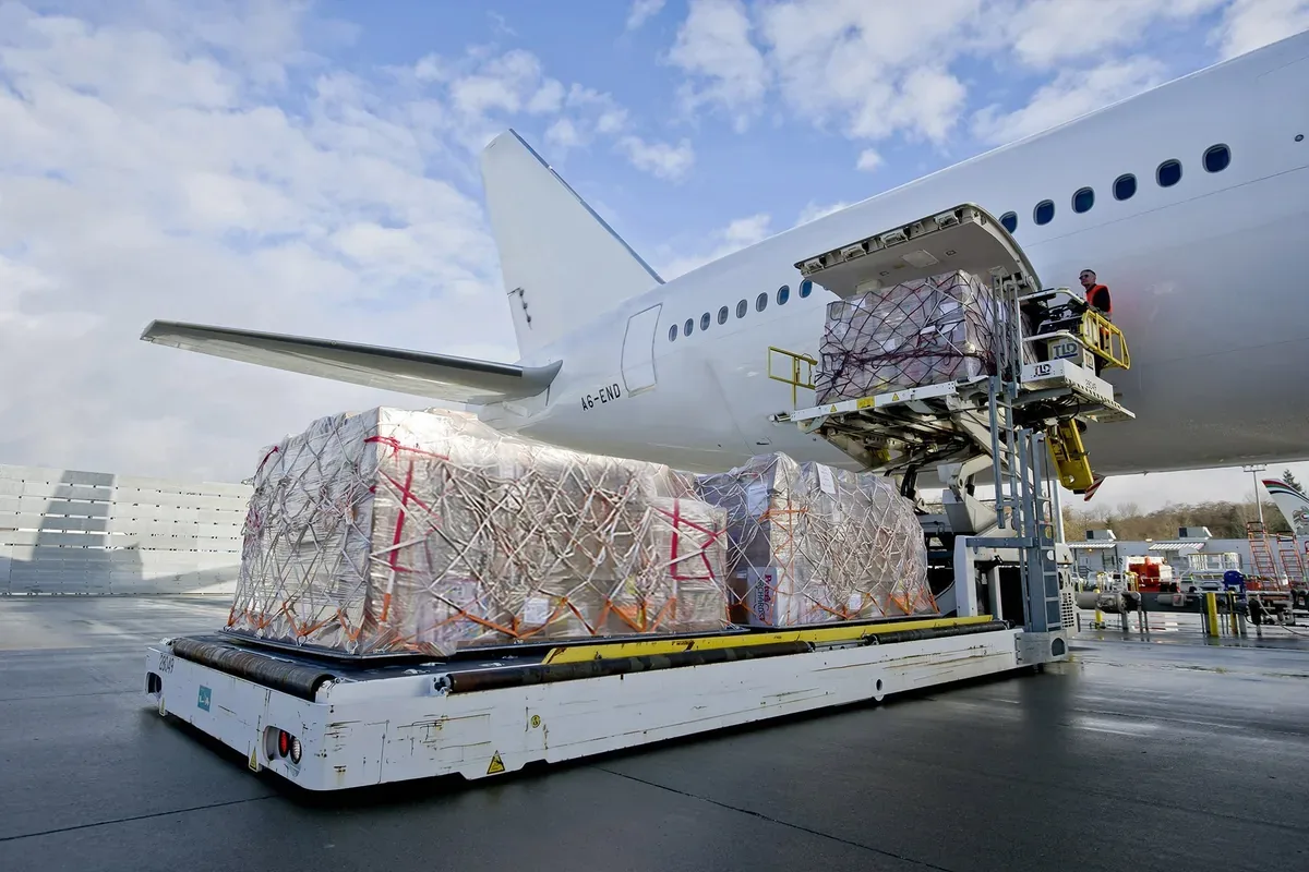 A wrapped cargo pallet being raised into an aircraft hold on the apron